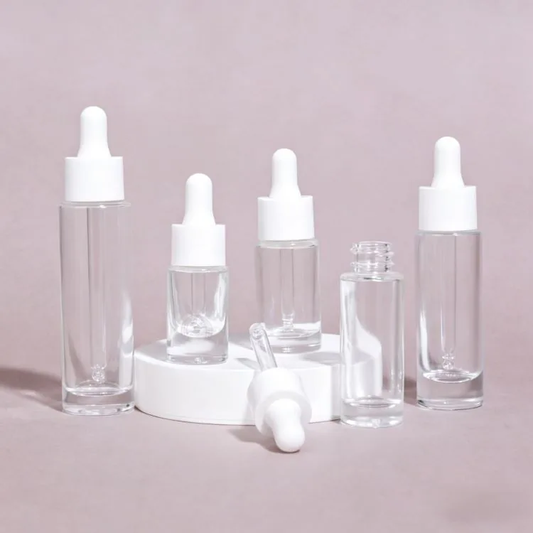 Clear round glass serum dropper bottles with white caps in assorted sizes